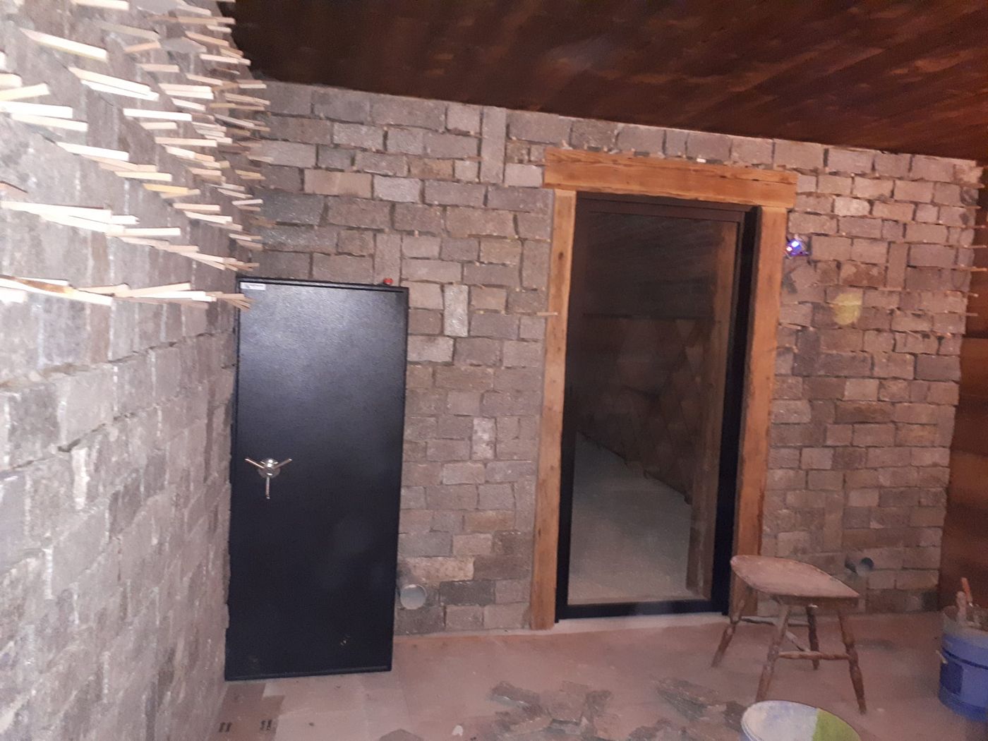 Mur de cave habillé de pierres naturelles autour d'une porte.