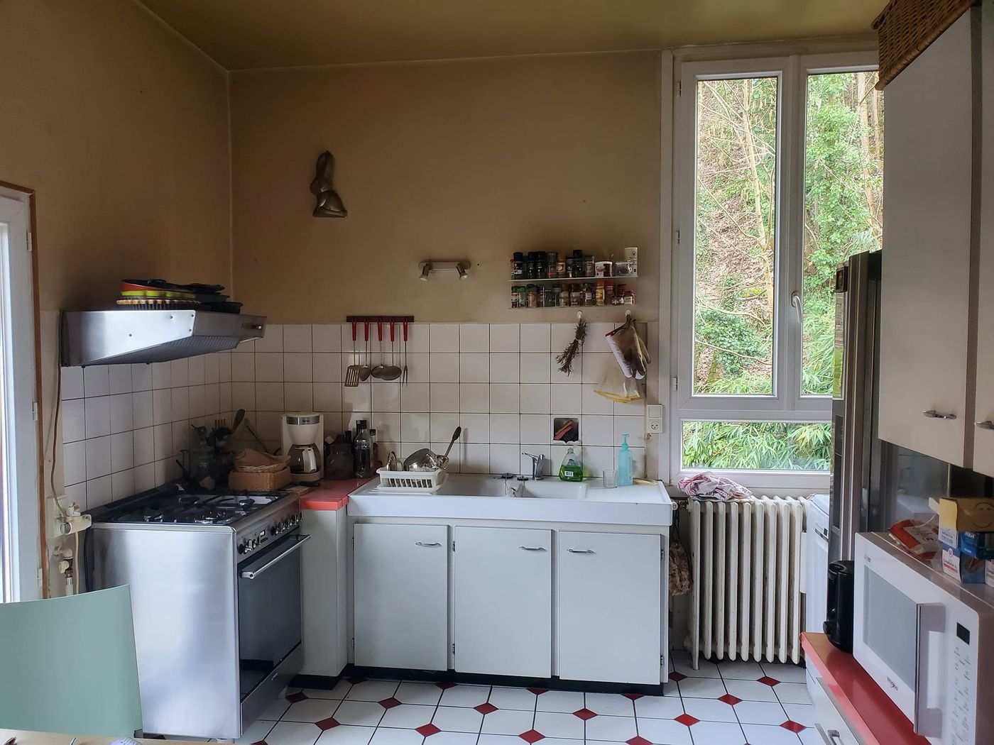 Cuisine avant travaux : murs jaunis, faïence ancienne et sol en damier.