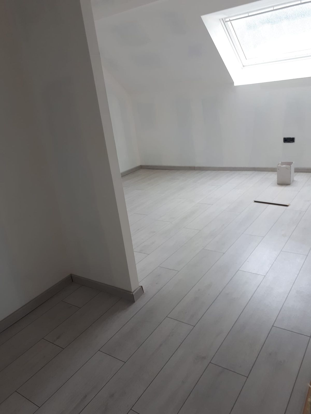 Pièce sous combles avec un parquet flottant clair fraîchement posé.
