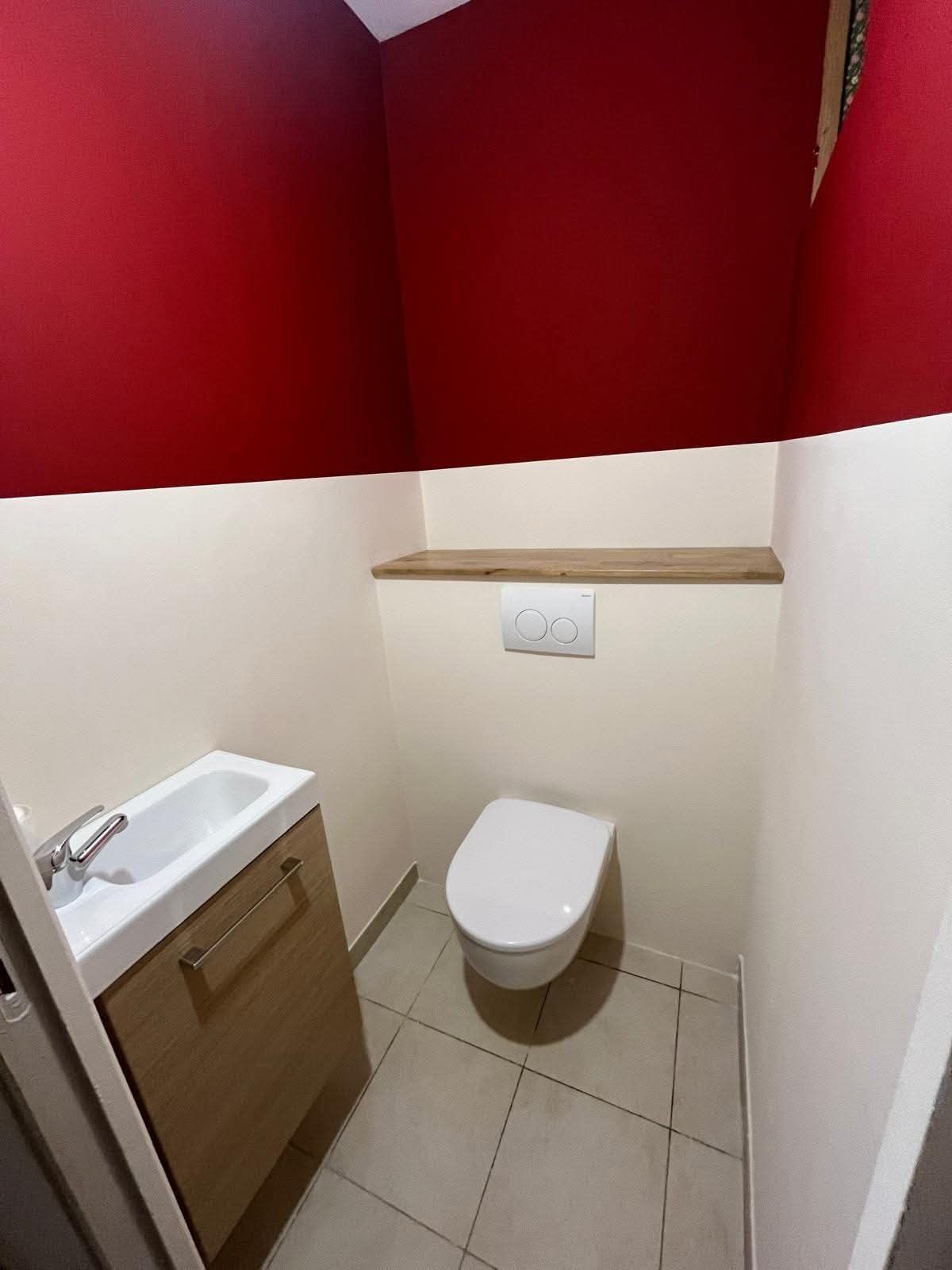 Toilettes repeintes en deux couleurs : rouge profond en partie haute, crème en partie basse, séparés par une ligne droite.