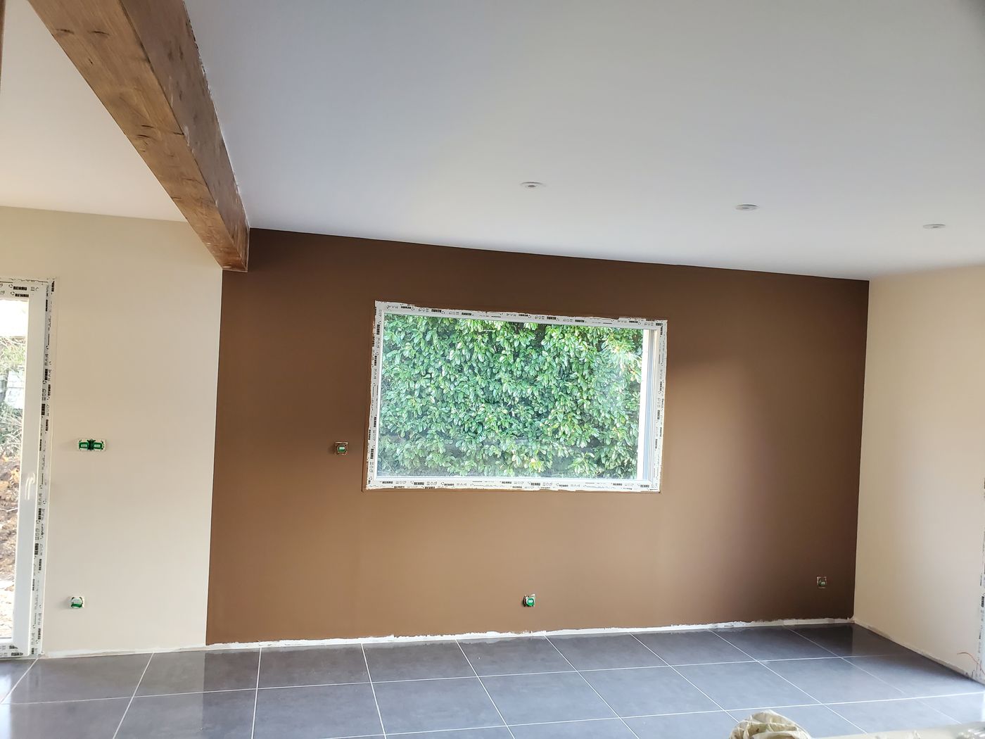 Pièce aux murs peints en brun taupe, plafond blanc et poutre apparente.